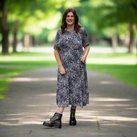 Woman in a patterned  breastfeeding dress standing on a path in a park