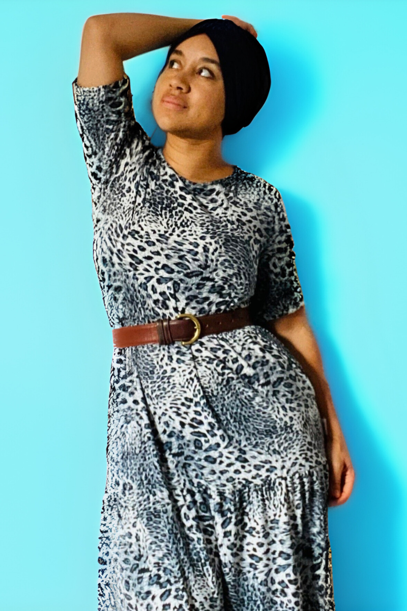 Woman wearing a leopard print breastfeeding dress against a blue background