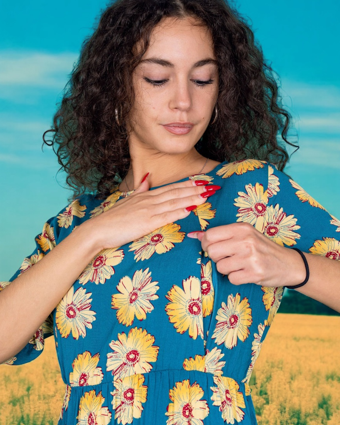 Woman wearing a blue floral dress against a bright blue sky. Showing zip breastfeeding dress access.