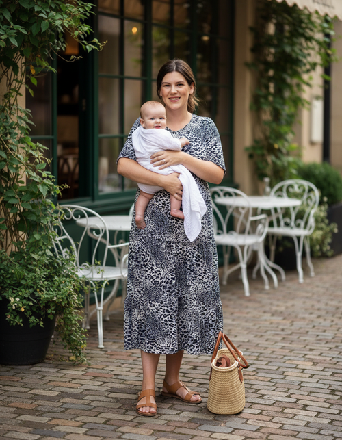 Model wearing MilkyMoon Grey Leopard Print Breastfeeding Midi Dress with hidden zip nursing access while holding a baby outdoors.