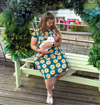 Woman in the a sunflower breastfeeding dress breastfeeding her baby showing the easy access zips for breastfeeding. 