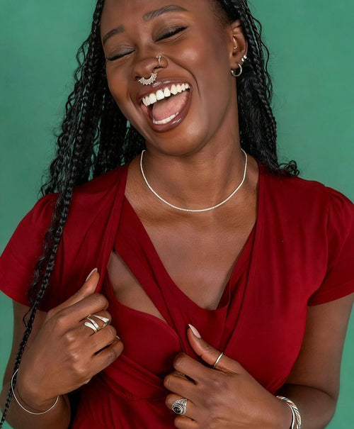 Woman in a red breastfeeding dress laughing against a green background