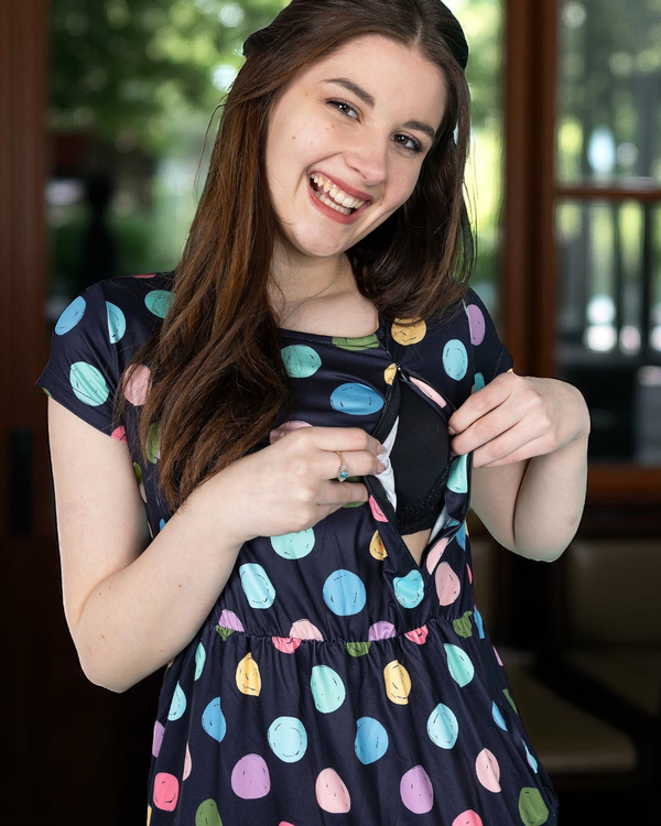 Woman wearing a navy breastfeeding dress with colorful polka dots, smiling outdoors.