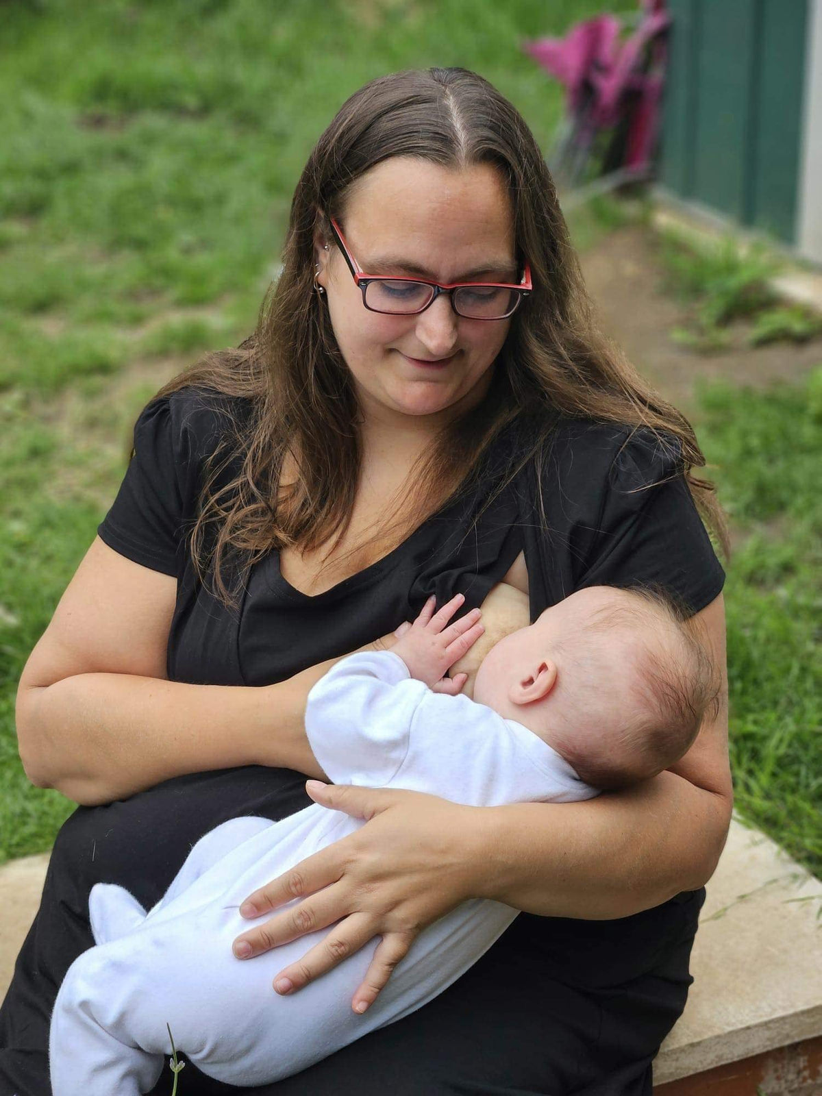mum sat down breastfeeding in. a black breastfeeding dress.